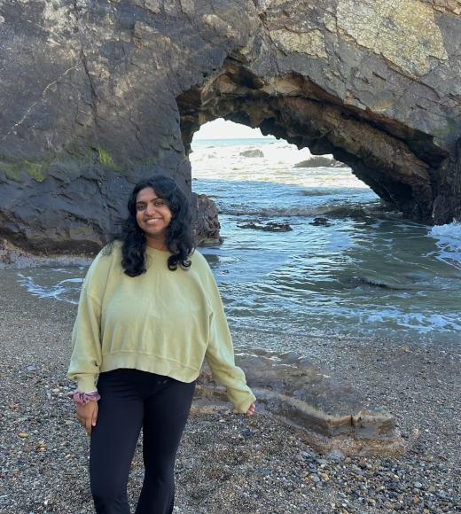 Adhithi profile picture in front of a giant gray rock and blue ocean in the background