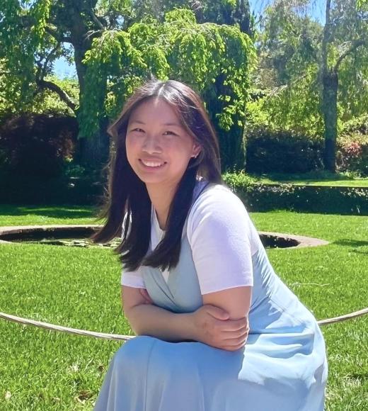 Photo of Ashley smiling in front of green field with green trees in the background