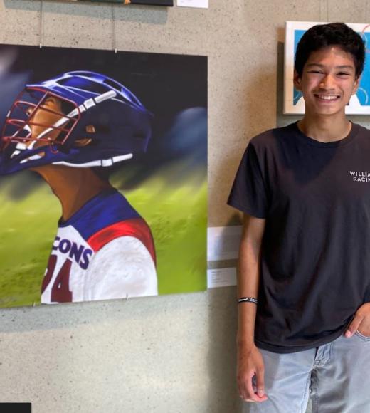 photo of Will wearing a black shirt and blue jeans standing next to a portrait of a baseball player