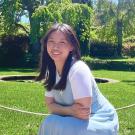 Photo of Ashley smiling in front of green field with green trees in the background